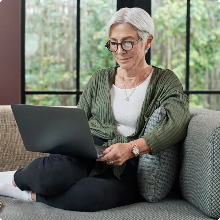 Woman sitting on couch working on a laptop